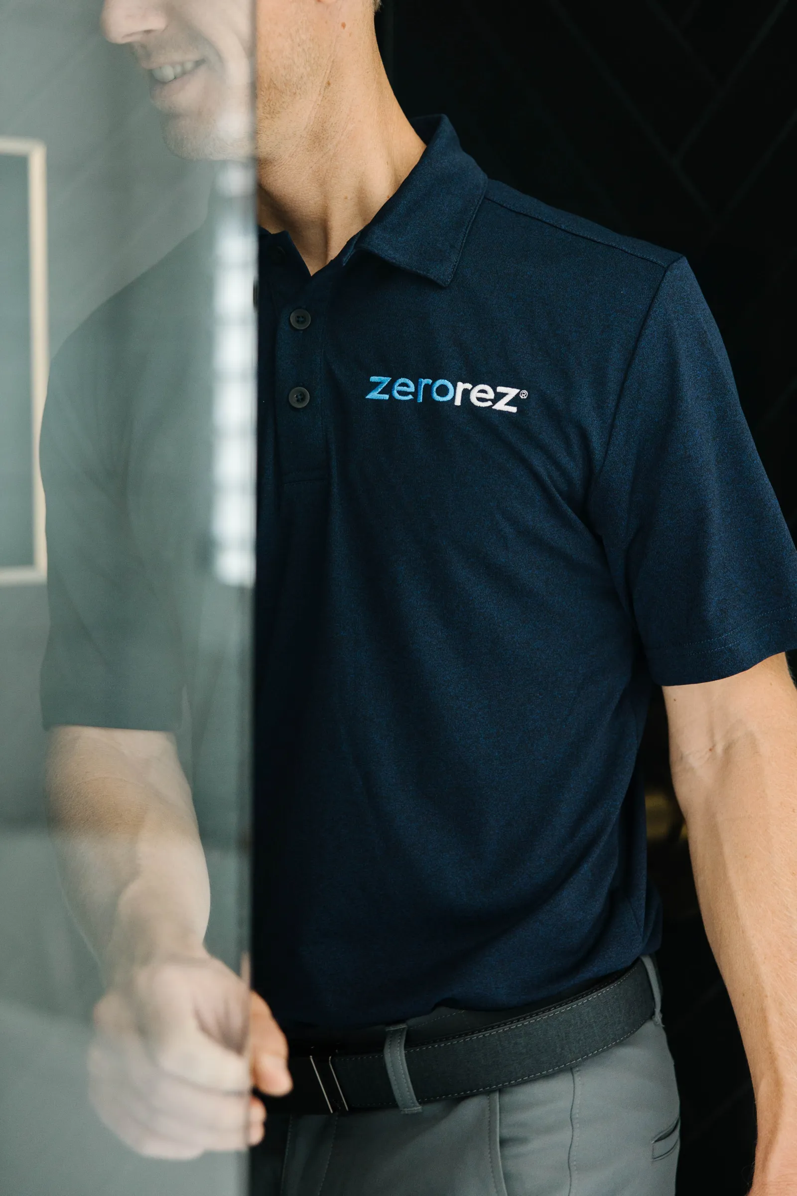 torso shot of a male Zerorez technician opening a glass shower enclosure door, inspecting it to clean it