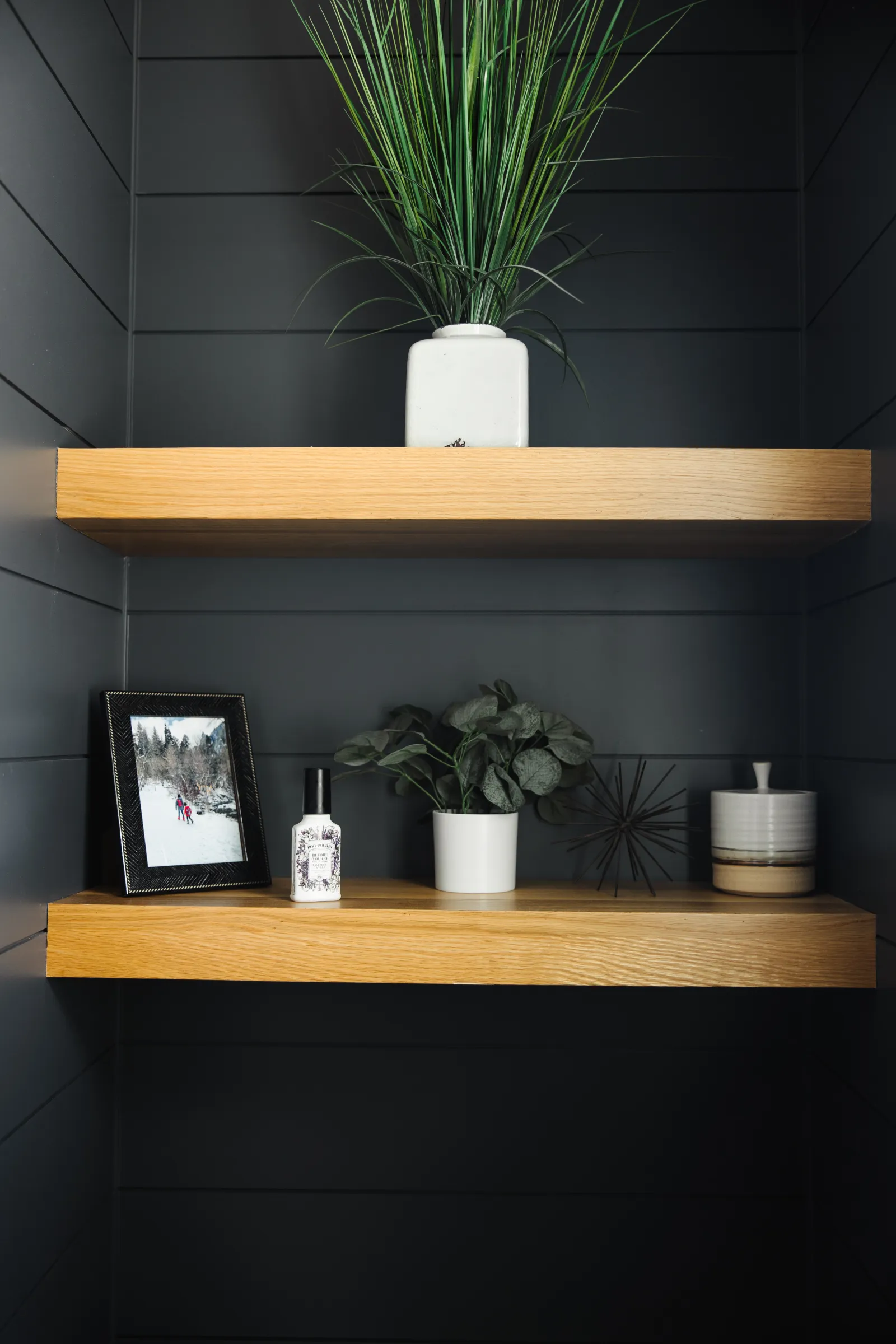 dusty bathroom shelves made of wood in a bathroom, with decor items like plants on them