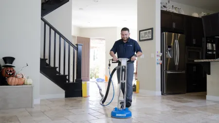Professional cleaner using a Zerorez machine to deep clean tile flooring in a modern home interior.