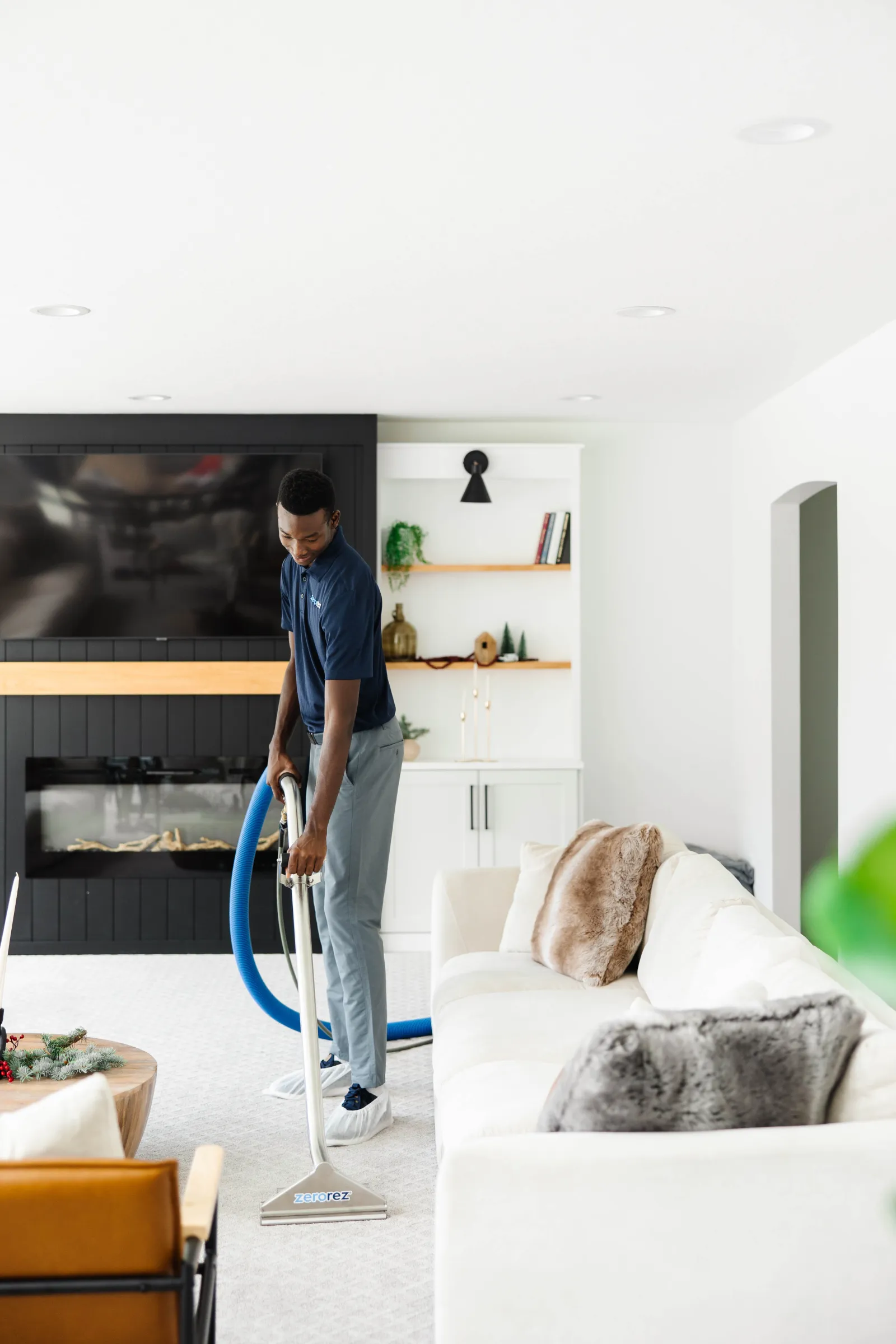 man cleaning white carpet in room with white couch