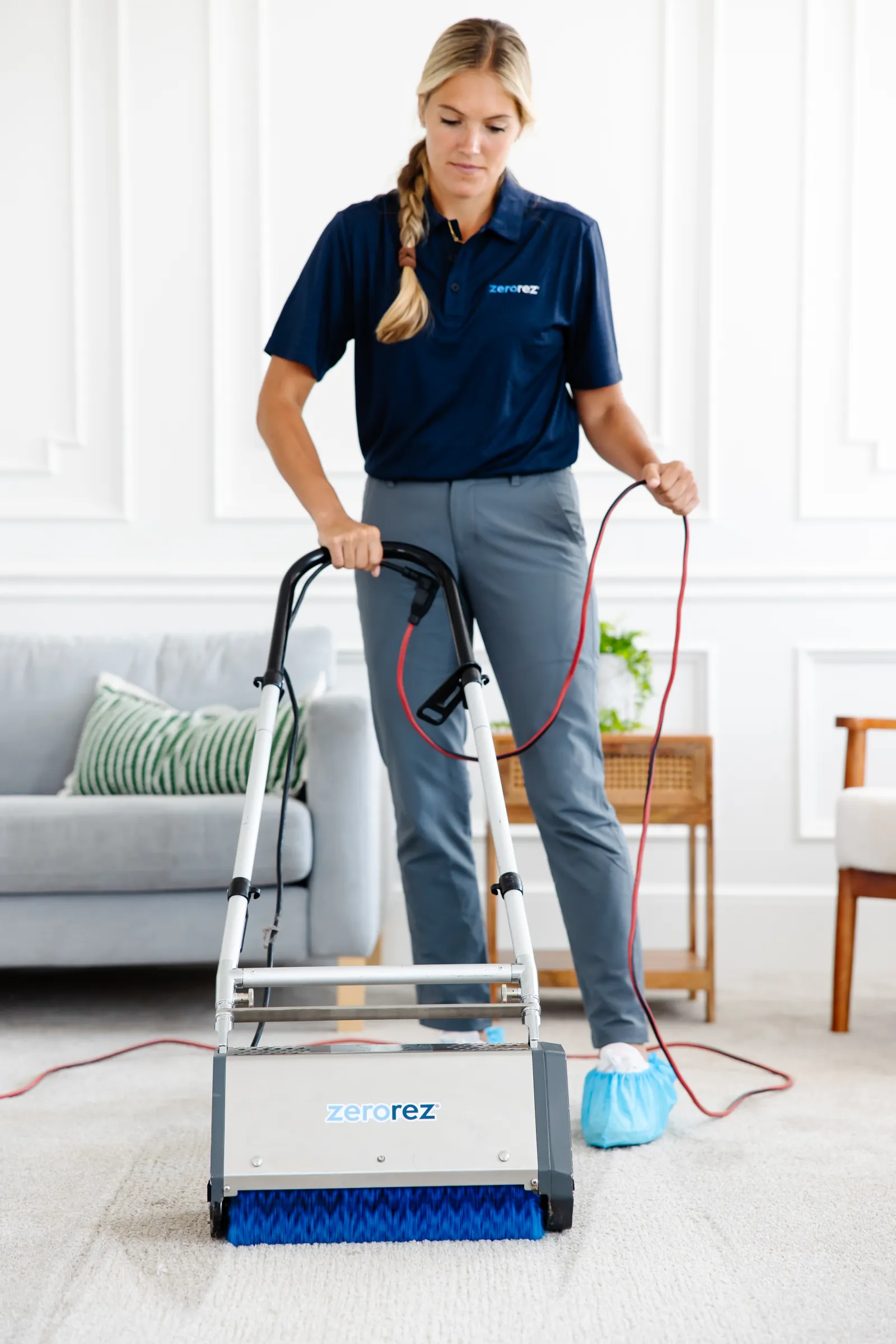 female Zerorez<sup>&reg;</sup> technician using the Zr<sup>&reg;</sup> Lifter to loosen and lift up all the embedded dirt in a carpet, working better than a vacuum
