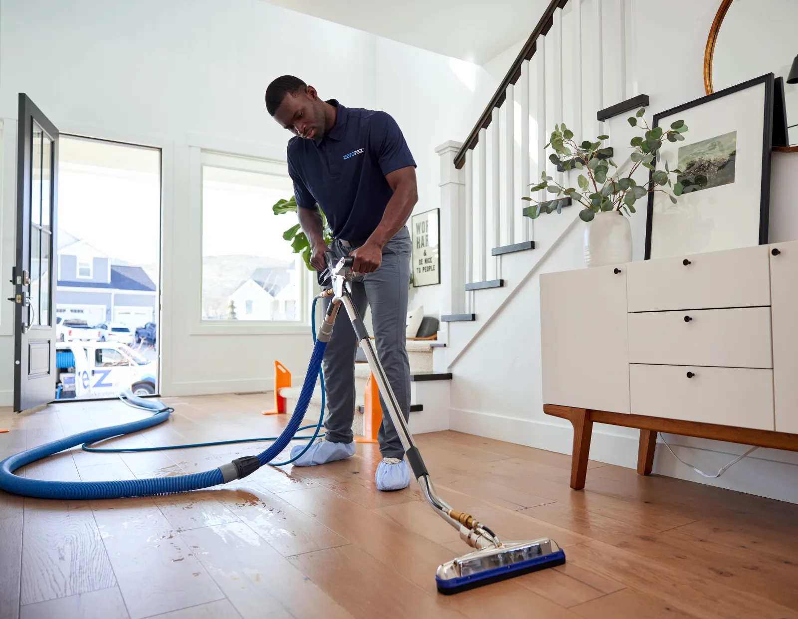 male black Zerorez&reg; technician professional cleaning hardwood floors in a home with the Zr&reg; Wand